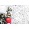 Red Christmas ornament hanging on snow covered spruce tree outside with copy space