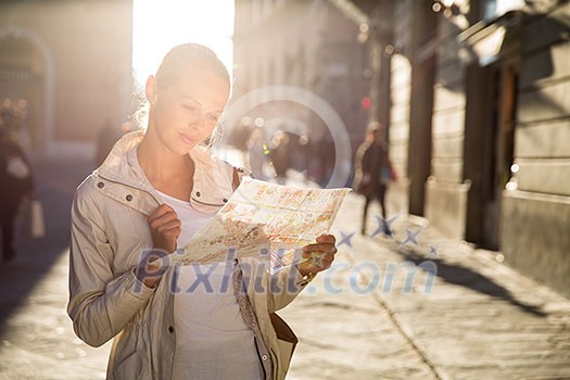 Gorgeous female tourist with a map discovering a foreign city (shallow DOF; color toned image)