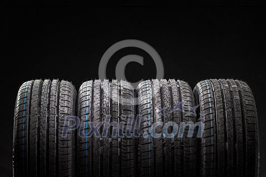 Stack of brand new high performance car tires on clean low-key black studio background Stack of brand new high performance car tires on clean low-key black studio background