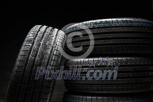 Stack of brand new high performance car tires on clean low-key black studio background Stack of brand new high performance car tires on clean low-key black studio background