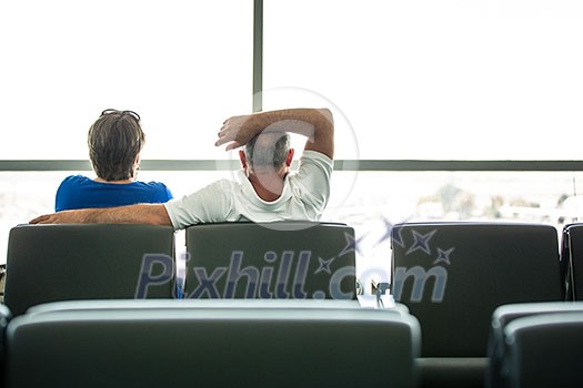 Senior couple waiting for their flight in an airport (shallow DOF; color toned image)