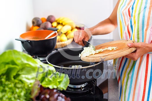 Young woman cooking in her modern kitchen (shallow DOF; color toned image)