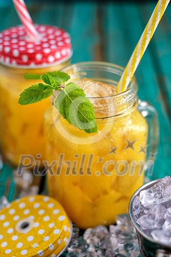 Fresh orange juice with ice in a mason jar on wooden table Fresh orange juice with ice in a mason jar on wooden table