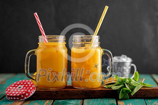Fresh orange juice with ice in a mason jar on wooden table Fresh orange juice with ice in a mason jar on wooden table