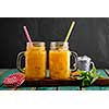 Fresh orange juice with ice in a mason jar on wooden table