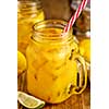 Fresh orange juice with ice in a mason jar on wooden table