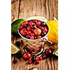 Small metal pail with different frozen berries on wooden table. Shallow depth of field. Rustic style.