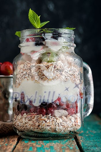 Muesli, fresh berries and yogurt in glass mason jar on wooden table. Healthy breakfast with Homemade granola