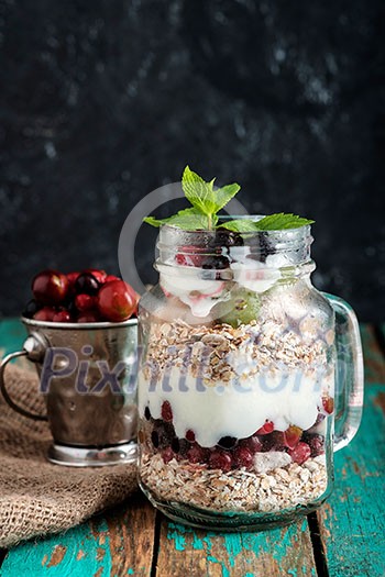 Muesli, fresh berries and yogurt in glass mason jar on wooden table. Healthy breakfast with Homemade granola