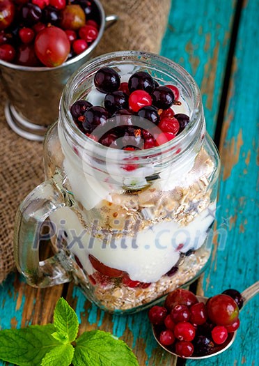 Healthy breakfast with Homemade granola. Muesli, fresh berries and yogurt in glass mason jar on wooden table. 