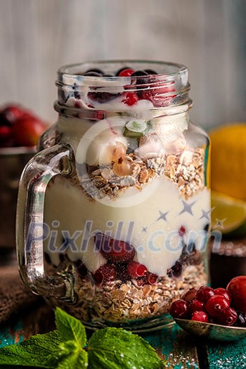 Muesli, fresh berries and yogurt in glass mason jar on wooden table. Healthy breakfast with Homemade granola