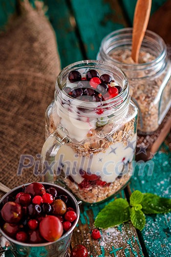 Muesli, fresh berries and yogurt in glass mason jar on wooden table. Healthy breakfast with Homemade granola