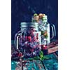 Fresh berries with ice in mason jar on dark background. Detox diet. Retro toned instagram style.