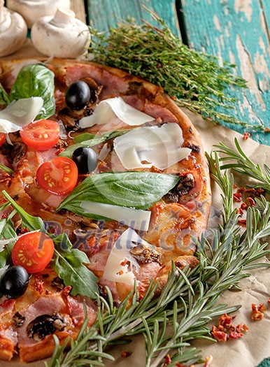Delicious fresh pizza with mushrooms and bacon on a wooden table.