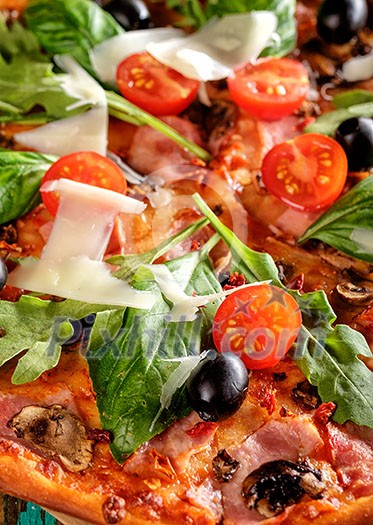 CLose-up of Homemade delicious pizza with bacon, tomatoes, olives and basil
