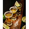 Mexican Gold Tequila with lime and salt on wooden table, selective focus.