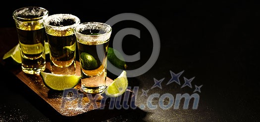 Mexican Gold Tequila with lime and salt on wooden table, selective focus. Copyspace on right. Mexican Gold Tequila with lime and salt on wooden table, selective focus. Copyspace on right.