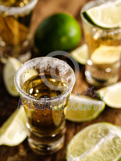 Mexican Gold Tequila with lime and salt on wooden table, selective focus. Shallow depth of field. Mexican Gold Tequila with lime and salt on wooden table, selective focus. Shallow depth of field.