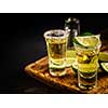 Two Gold tequila shots with lime, copy space on left side. Gold Mexican tequila on wooden background. Alcohol drink, selective focus.