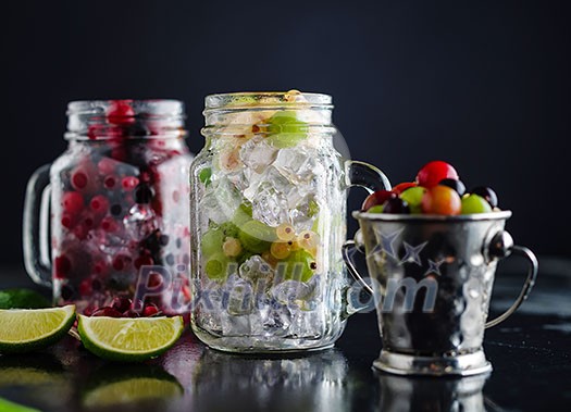 Fresh berries with ice in mason jar on dark background. Detox diet.