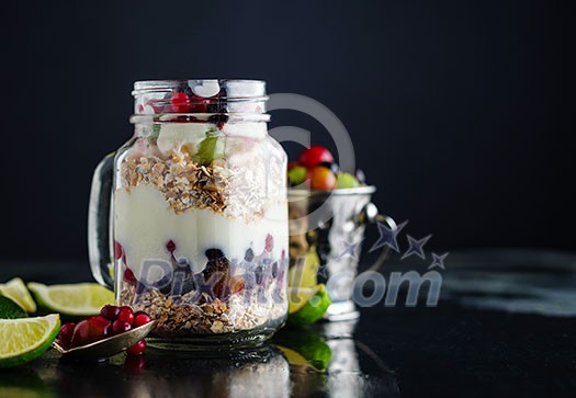 Muesli, fresh berries and yogurt in glass mason jar on wooden table. Healthy breakfast with Homemade granola