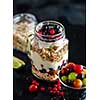 Muesli, fresh berries and yogurt in glass mason jar on wooden table. Healthy breakfast with Homemade granola