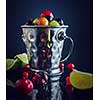 Small metal pail with different berries on dark table. Shallow depth of field. Rustic style. Toned.