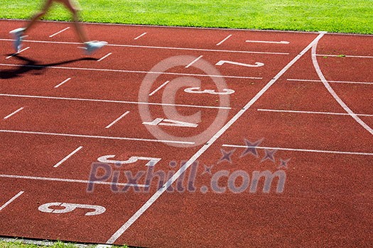 Runner on a running track finishing a race first (motion blurred image) Runner on a running track finishing a race first (motion blurred image)