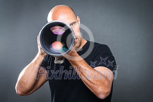 Young, pro male photographer in his studio during a photo shoot (color toned image; shallow DOF)