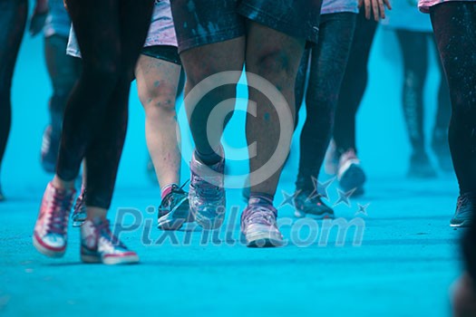 People participating in the Color Run - Runners' legs amid blue powder People participating in the Color Run - Runners' legs amid blue powder