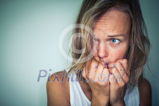 Young woman suffering from a severe depression, anxiety/sudden fear (very harsh lighting is used on this shot to underline/convey the gloomy mood of the scene; color toned image)