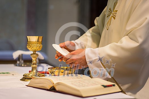 Priest during a wedding ceremony/nuptial mass (shallow DOF; color toned image)