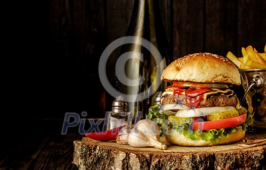 Delicious homemade hamburger with lettuce and cheese. Fried chips and burger on wooden background.