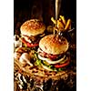 Delicious homemade hamburger with lettuce and cheese. Fried chips and burger on wooden background.