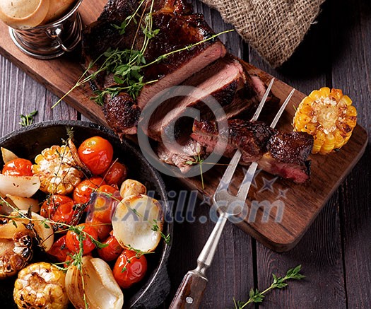 Grilled steak sliced on a cutting board. Entrecote with vegetables on a wooden background. Grilled steak sliced on a cutting board. Entrecote with vegetables on a wooden background.