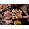 Close-up of piece grilled steak on a fork. Grilled steak sliced on a cutting board. Entrecote with vegetables on a wooden background. 