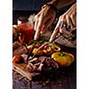 Grilled steak sliced on a cutting board. Entrecote with vegetables on a wooden background. Woman slicing a grilled beef stead.