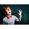 Smart boy in red glasses near blackboard with formulas