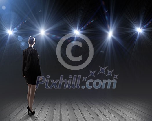Rear view of businesswoman standing in lights of stage