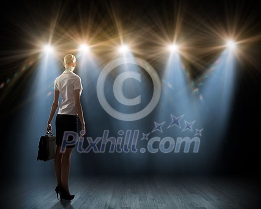 Rear view of businesswoman standing in lights of stage Rear view of businesswoman standing in lights of stage