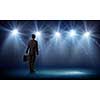 Rear view of businessman standing in lights of stage