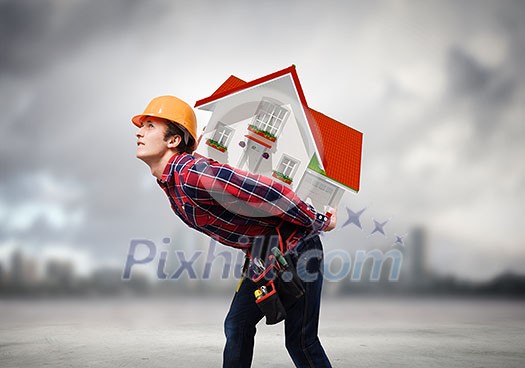 Young smiling craftsman carrying house model on back Young smiling craftsman carrying house model on back