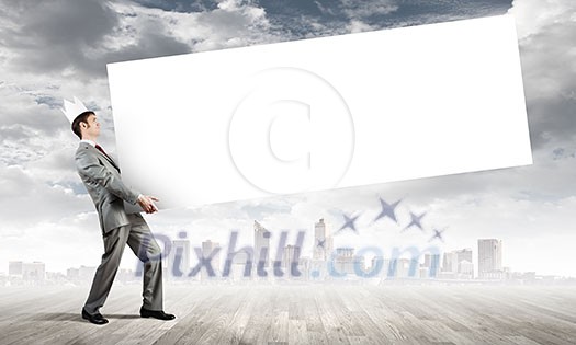 Young businessman wearing crown and carrying white blank banner. Place for text Young businessman wearing crown and carrying white blank banner. Place for text