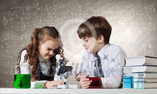 Cute girl and boy at chemistry lesson making tests Cute girl and boy at chemistry lesson making tests