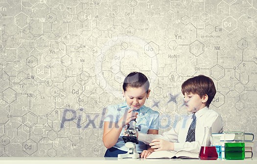 Cute girl and boy at chemistry lesson making tests Cute girl and boy at chemistry lesson making tests