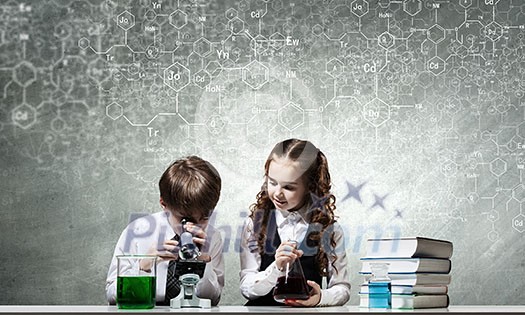 Cute girl and boy at chemistry lesson making tests Cute girl and boy at chemistry lesson making tests