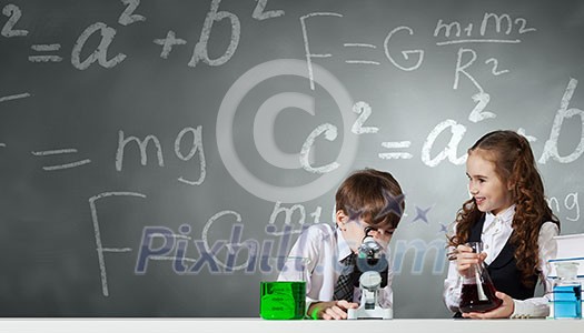 Cute girl and boy at chemistry lesson making tests Cute girl and boy at chemistry lesson making tests