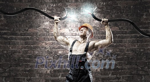 Strong man in uniform tearing electricity cable with hands Strong man in uniform tearing electricity cable with hands