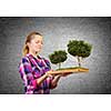 Young woman in casual holding opened book with green tree