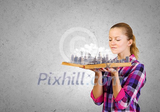 Young woman in casual holding opened book with city model Young woman in casual holding opened book with city model